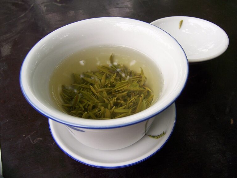 A cup of green tea with loose leaves