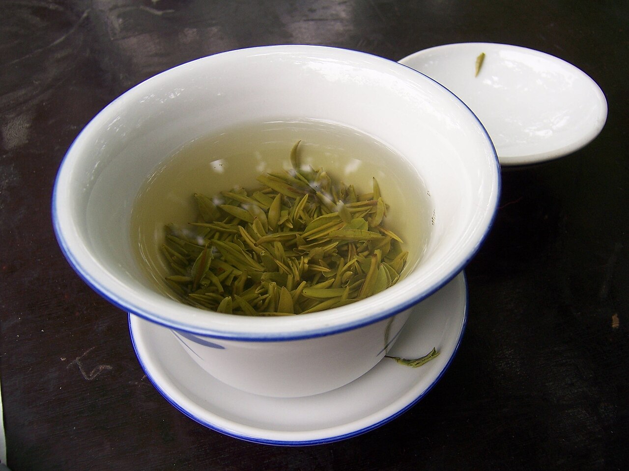 A cup of green tea with loose leaves