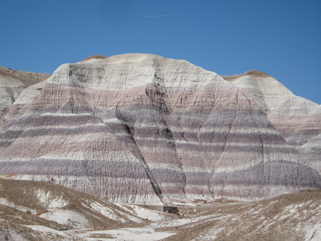 Grey and white banded bentonite clay hills under a blue sky