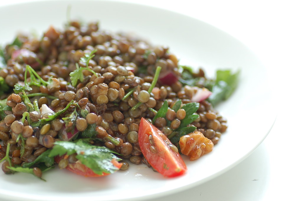Green lentil salad with tomatoes in a white bowl