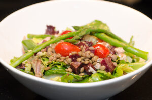 A bowl of lentil salad with tomatoes and greens