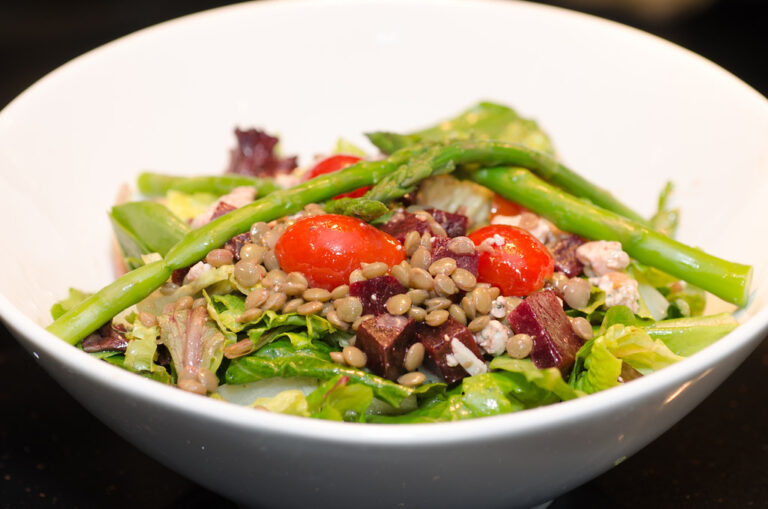 A bowl of lentil salad with tomatoes and greens
