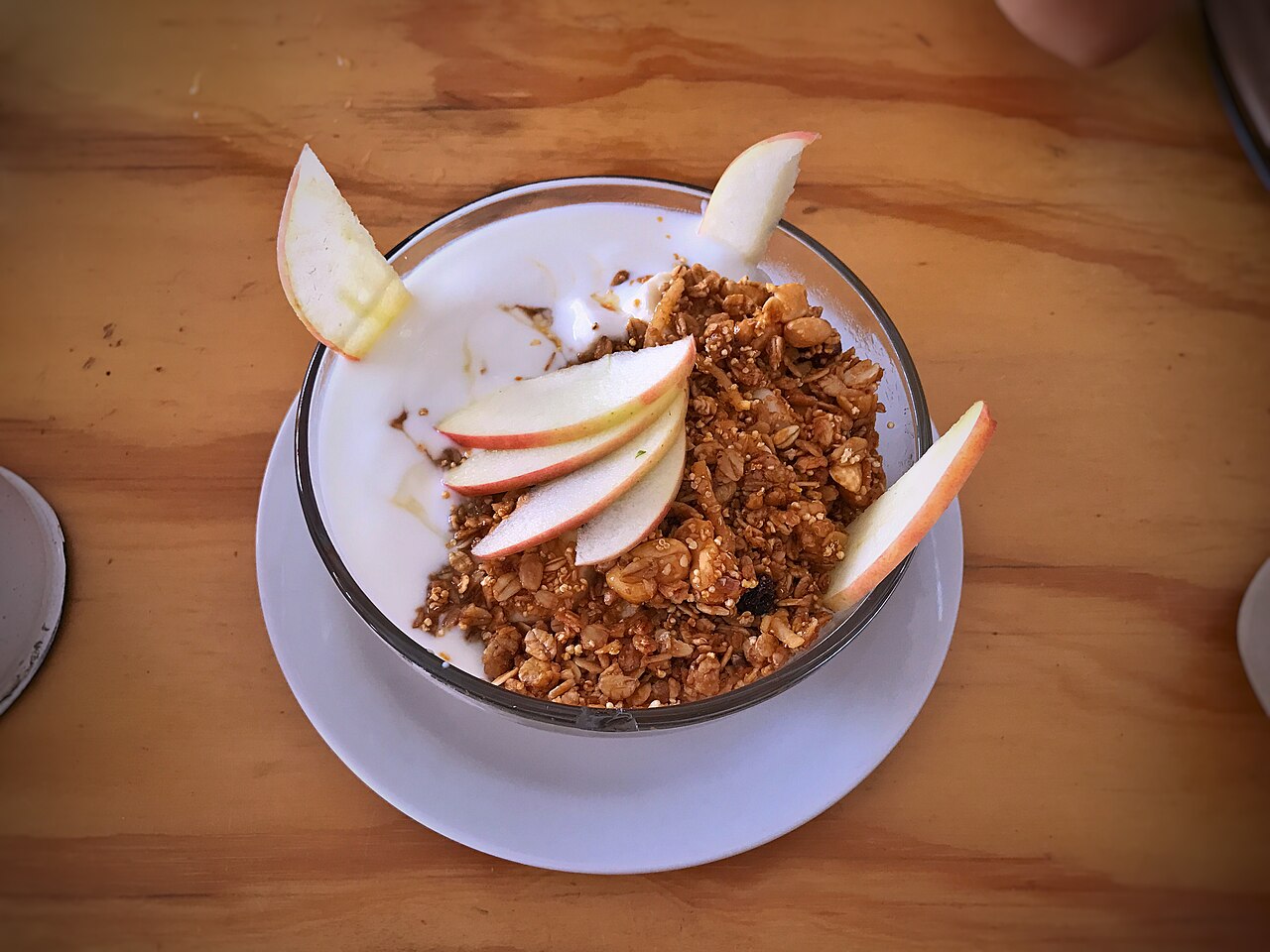 A bowl of yogurt topped with granola and apple slices