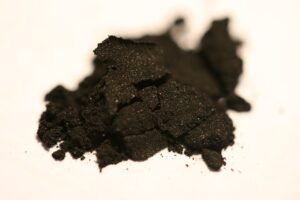 A small heap of fine black charcoal powder on a white surface