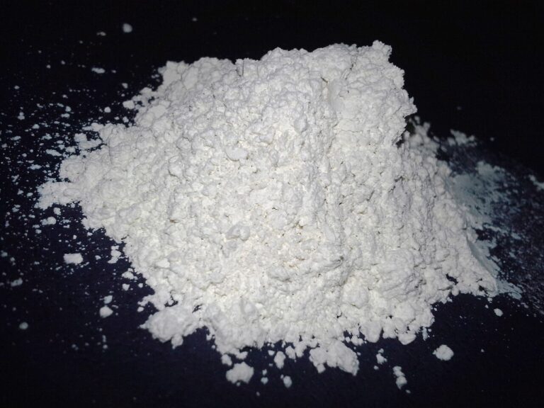 A small heap of white food-grade diatomaceous earth powder on a dark background