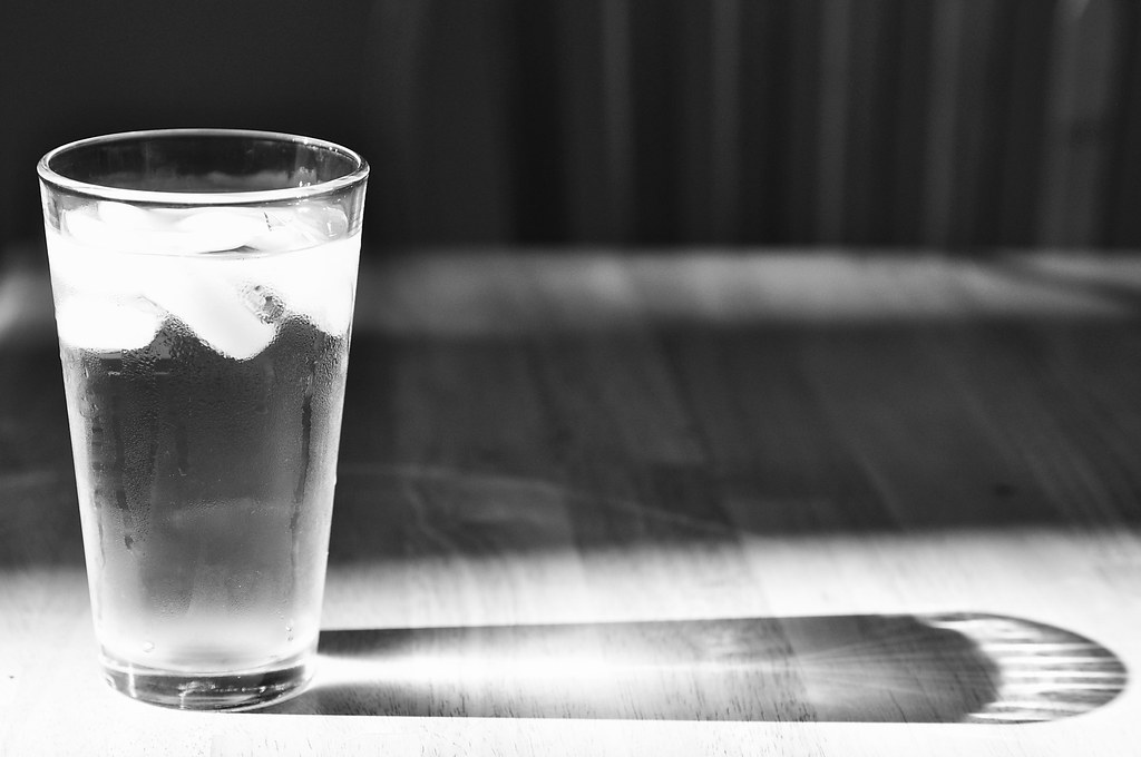 A tall glass of water with ice on a table
