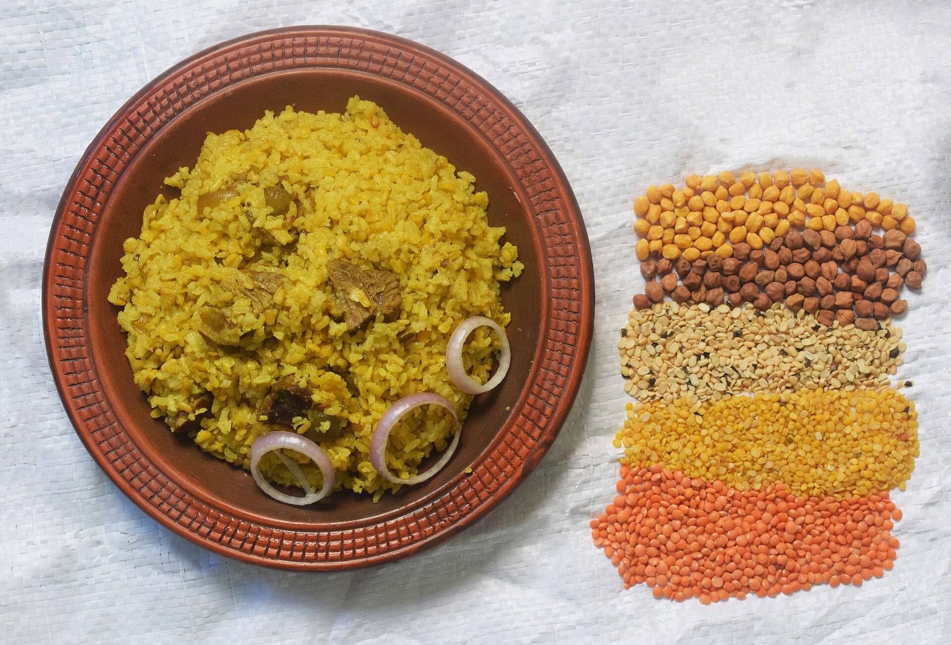 A bowl of yellow kitchari beside small piles of rice and lentils
