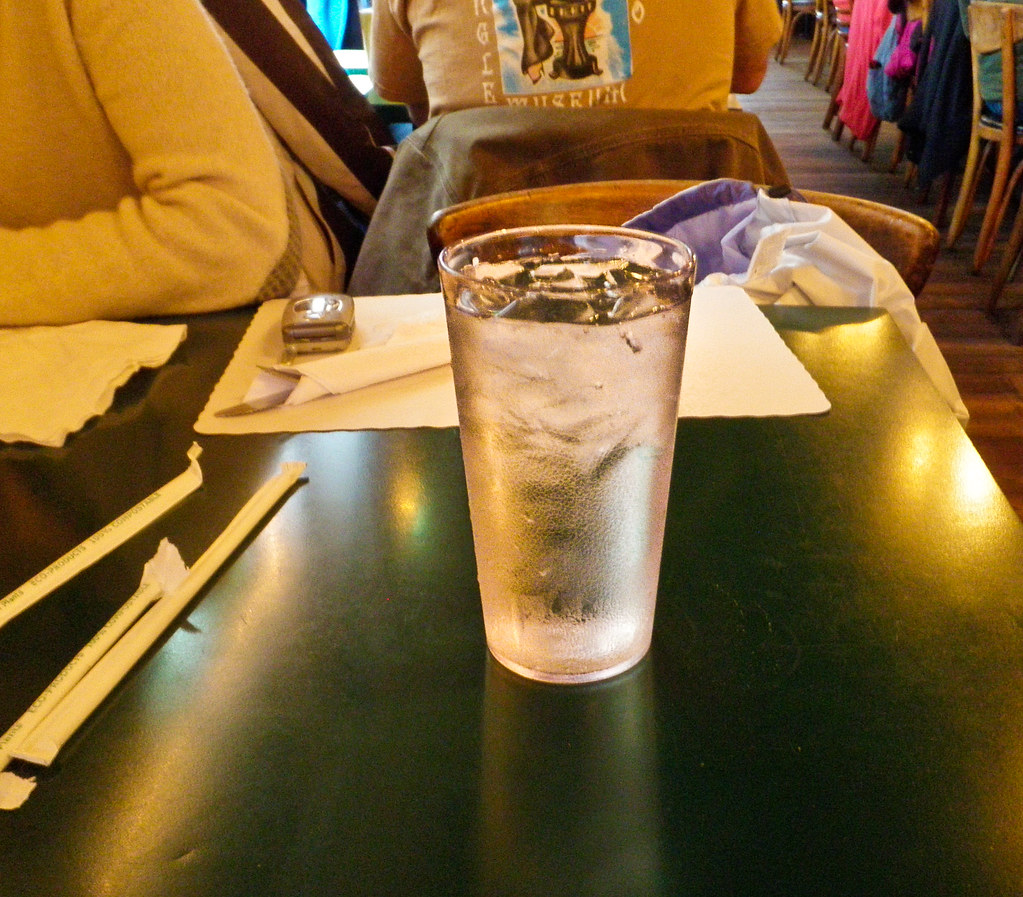 A tall glass of cold water on a table