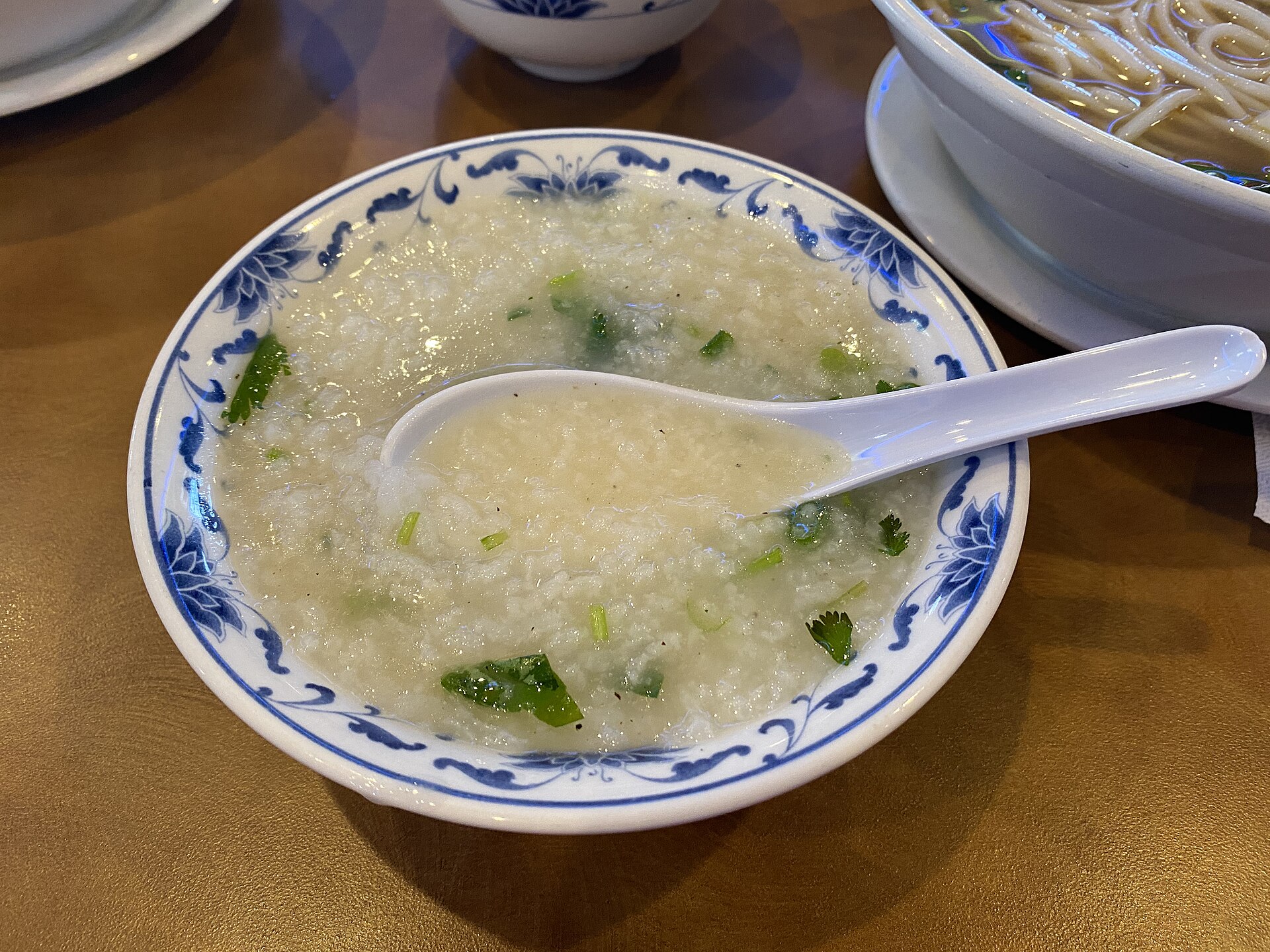A bowl of plain rice congee with a spoon