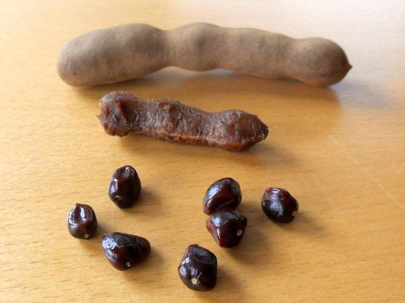 Ripe tamarind pods, some broken open to show the sticky brown pulp inside
