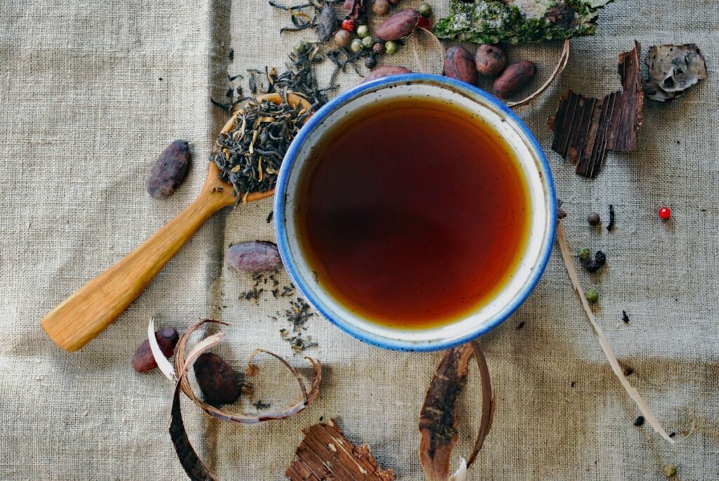 Cup of herbal tea surrounded by dried herbs