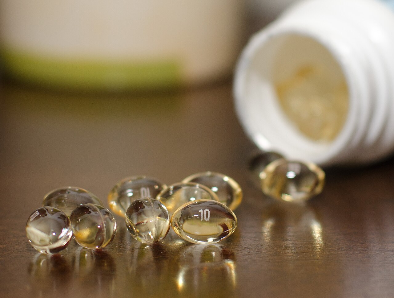 Clear golden softgel capsules spilling from a supplement bottle
